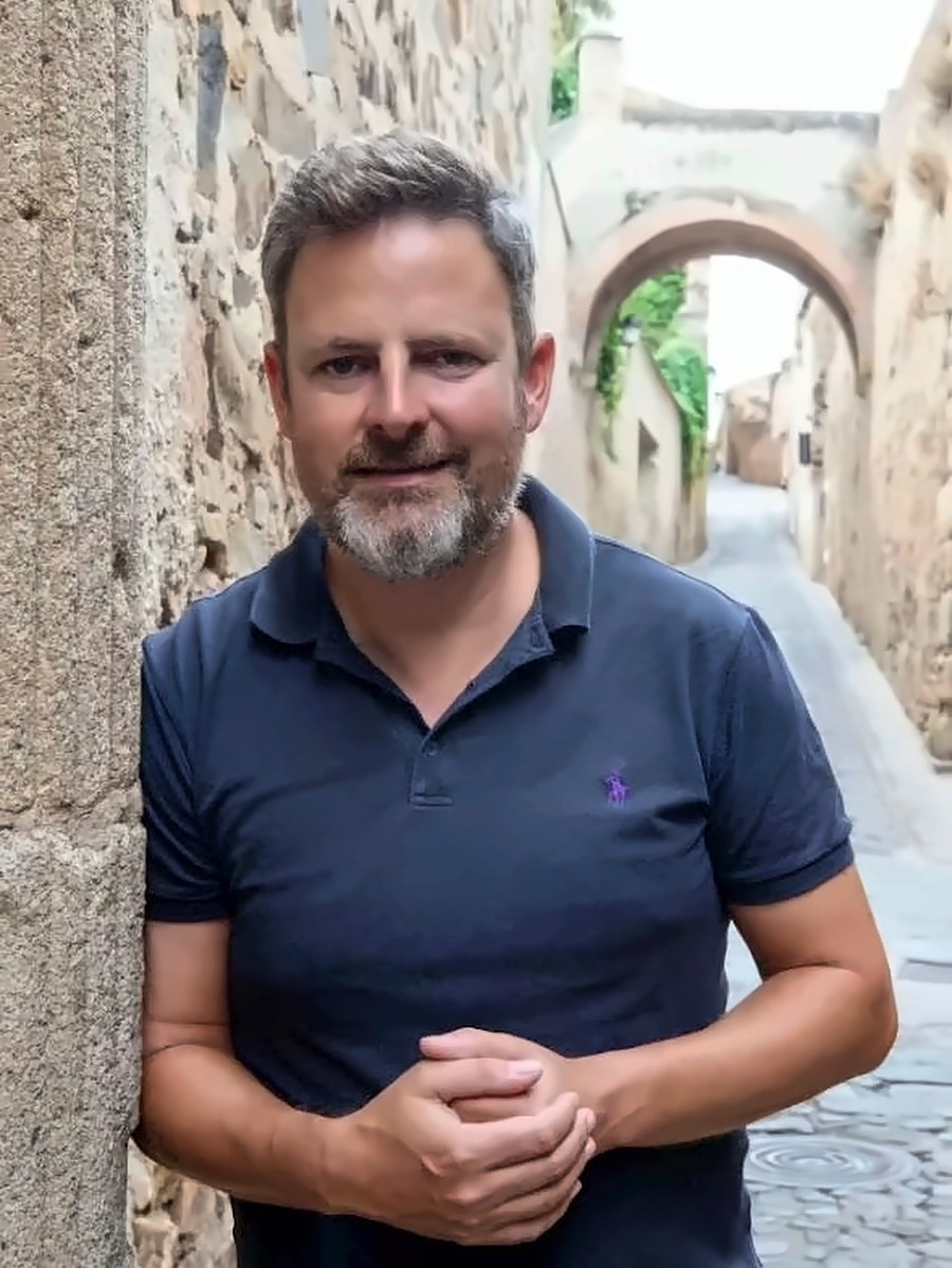 Jorge Villar Guijarro apoyado en un muro de piedra en una calle de la ciudad monumental de Cáceres