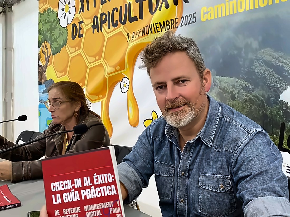 Jorge Villar en la mesa de presentación de «Check-in al éxito» en la XI Feria Internacional de Apicultura y Turismo de Caminomorisco, con el libro en primer plano