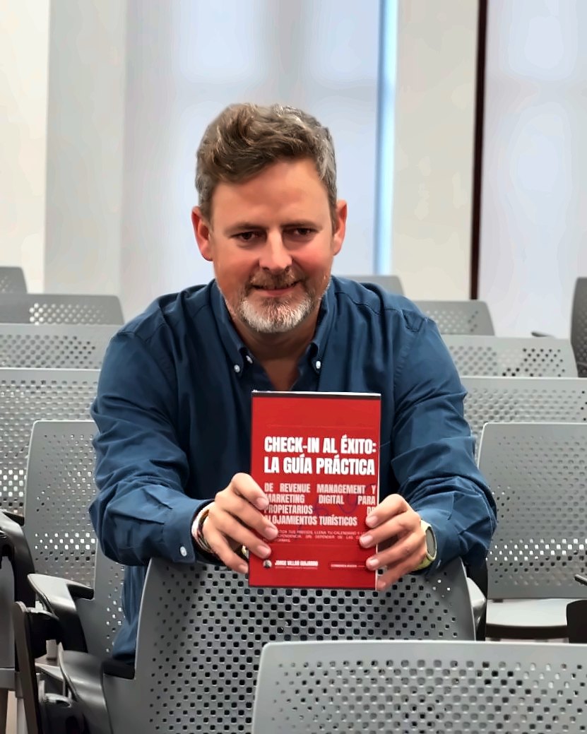 Jorge Villar Guijarro sostiene un ejemplar de «Check-in al éxito» en una sala de conferencias
