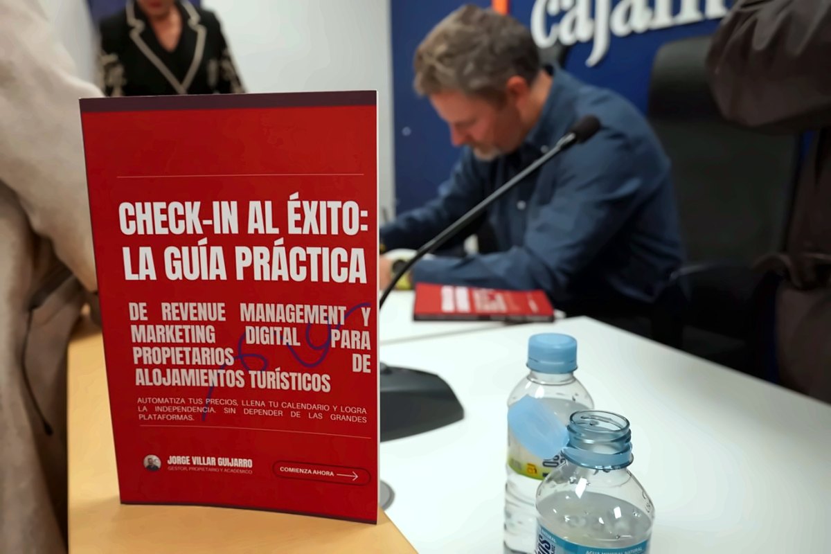 Presentación de «Check-in al éxito» en Caja Almendralejo, Cáceres, con el libro en primer plano y el autor firmando ejemplares al fondo
